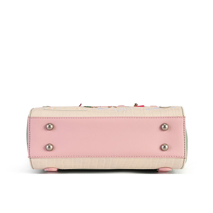 The bottom view of a structured handbag in light pink and beige textured leather, featuring silver-tone metal studs on the front panel and small pink feet at the base, set against a plain white background.