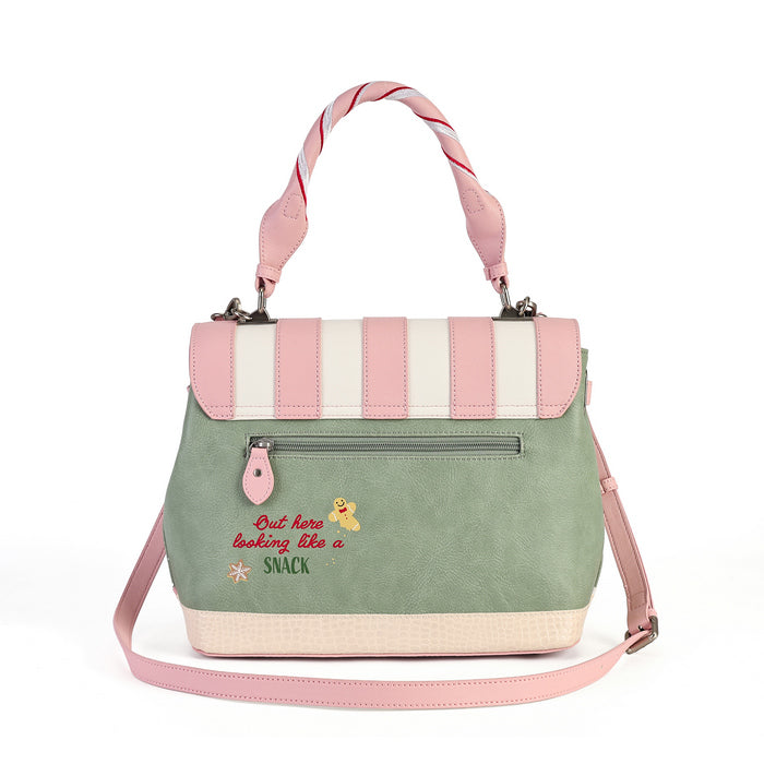 A pastel green and pink handbag with a striped top flap, pink twisted top handles, a front zip pocket, and embroidered text reading 'But here looking like a SNACK' on a white background.
