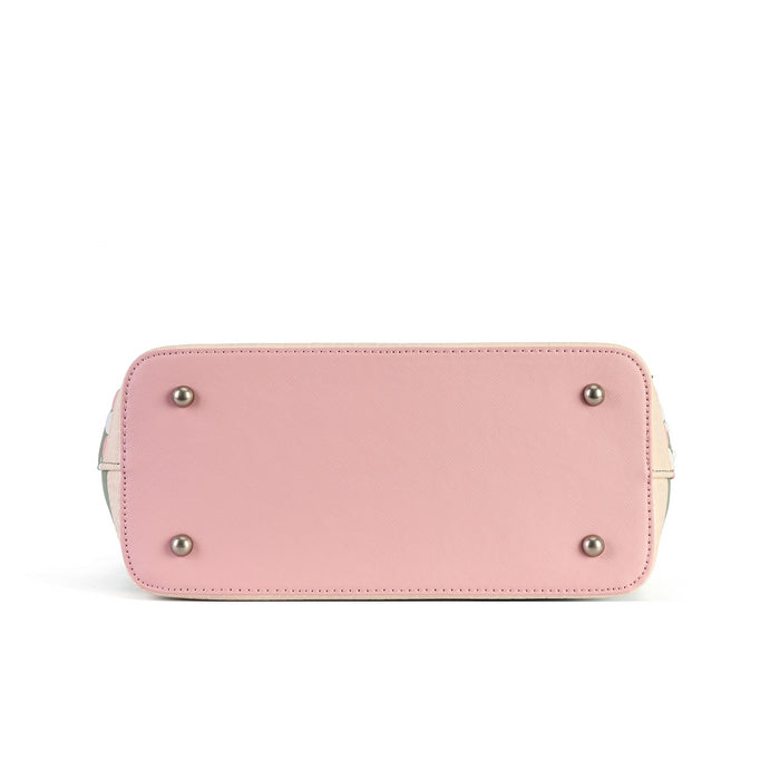The bottom view of a light pink leather handbag, showing a smooth finish, stitched edges, and four silver metal studs on a white background.