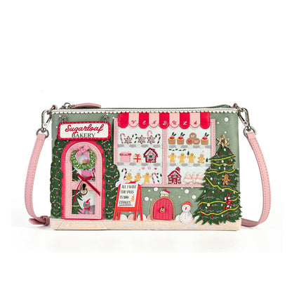 A rectangular shoulder bag with a detailed Christmas bakery storefront design, featuring pink straps and silver-tone hardware, set against a plain white background.