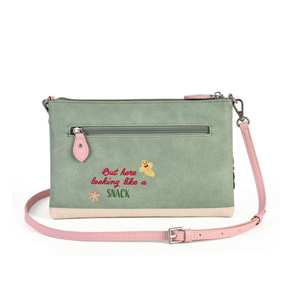 A sage green faux-leather crossbody clutch bag with a pink strap, featuring a front zip pocket, embroidered text reading 'Out here looking like a SNACK', and a small bee graphic, shown on a white background.