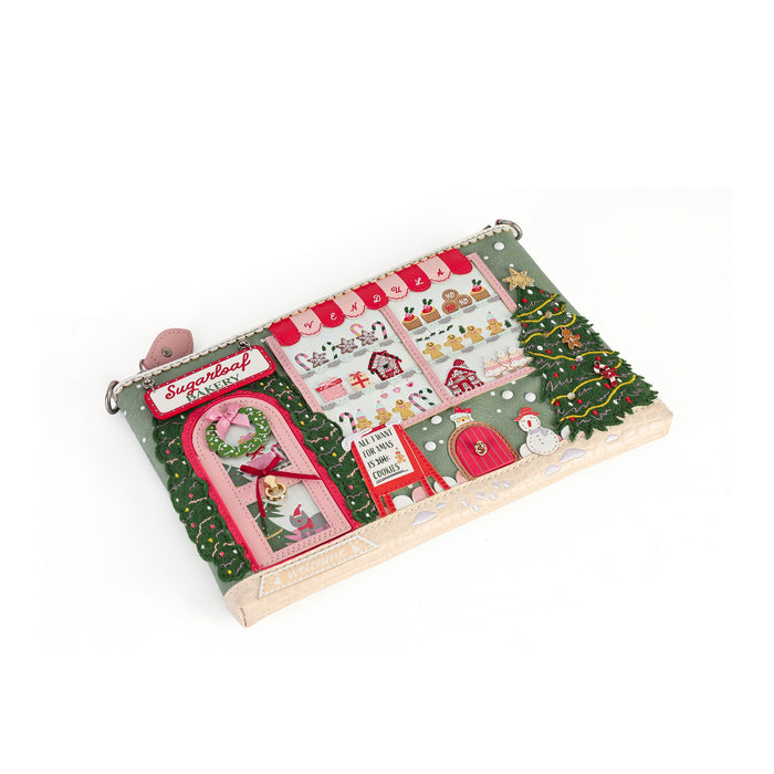 A wooden advent calendar toy with a Christmas village theme, featuring colorful felt windows, stockings, a tree, and a sleigh on a white background.