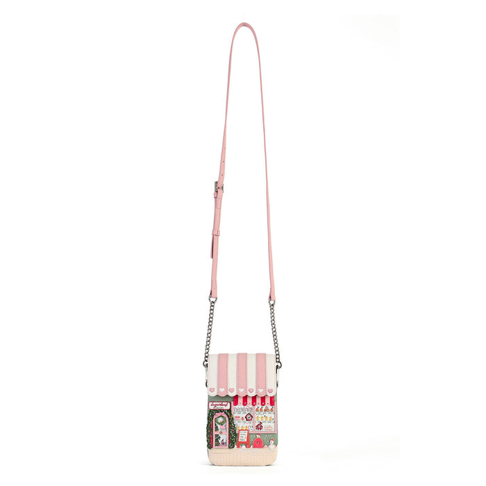 A pink faux-leather crossbody bag with a long shoulder strap and silver chain links, featuring a whimsical storefront graphic on the front pocket with strawberries, a cat, and the text 'Café Strawberry'.