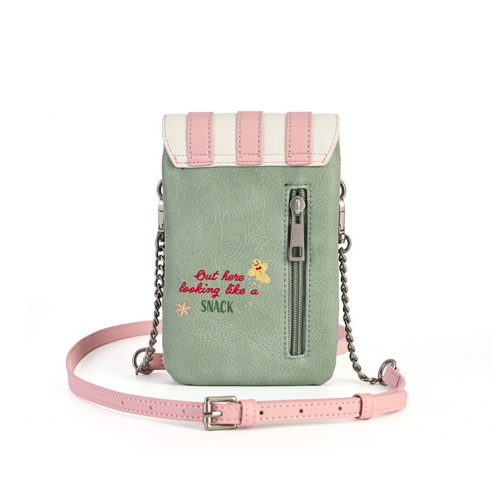 A small crossbody phone bag in sage green faux leather with a pink and cream flap, a vertical front zipper, silver chain straps, and a pink adjustable strap. The front features embroidered text reading 'But here looking like a SNACK' with a small yellow cartoon snack character.