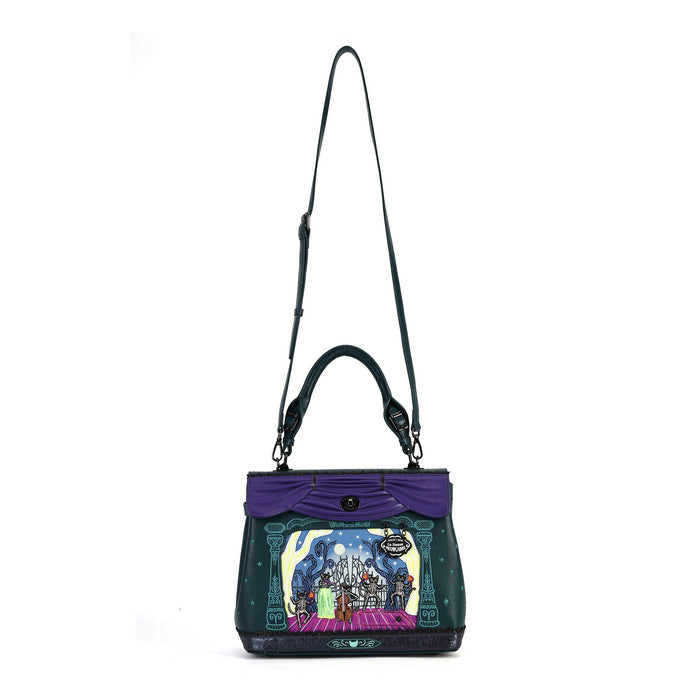A dark teal and purple handbag with a colorful cartoon character illustration on the front, featuring a purple top handle, a long shoulder strap, and a black base, shown against a plain white background.