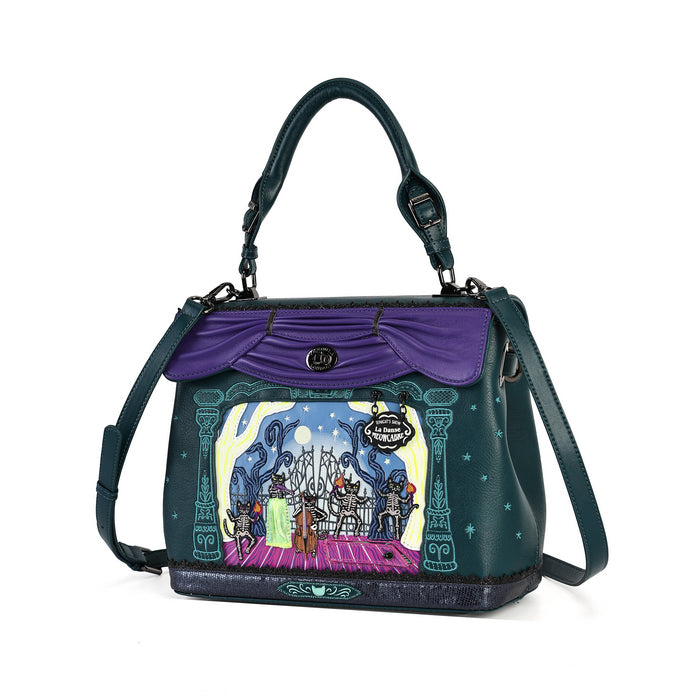 A dark teal and purple handbag with a whimsical illustrated scene on the front depicting a fantasy castle and characters under a starry sky. The bag features a purple draped flap, a top handle, and a detachable shoulder strap, set against a plain white background.