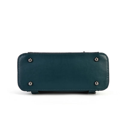 The bottom base of a teal leather clutch or wallet, featuring four silver metal studs and a zippered top closure, shown on a plain white background.
