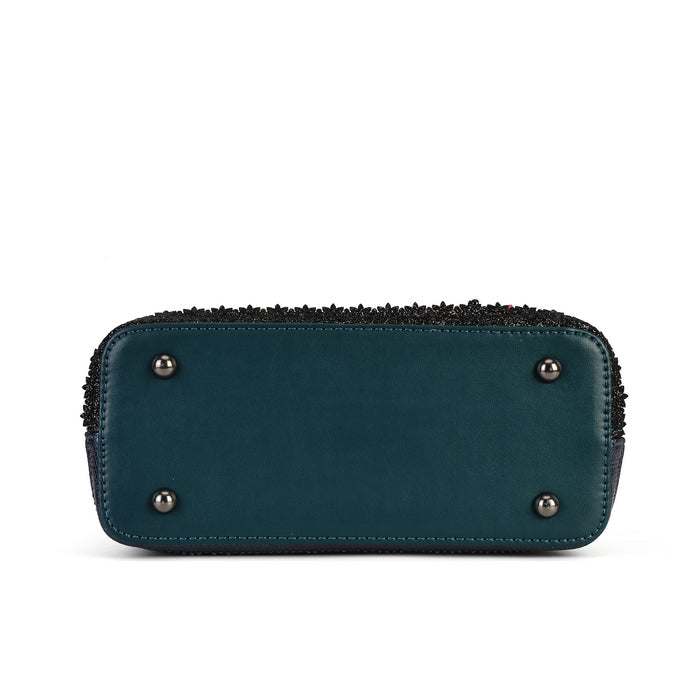 The bottom view of a teal blue leather clutch or zip-around wallet, featuring four silver metal studs on the front and a black textured fringe trim along the top zipper edge, set against a plain white background.