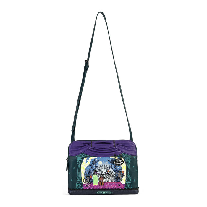 A purple and dark green crossbody bag featuring a colorful, whimsical fantasy illustration on the front depicting a castle and a character holding a green gift. The bag has a long dark green strap and a small hanging charm.