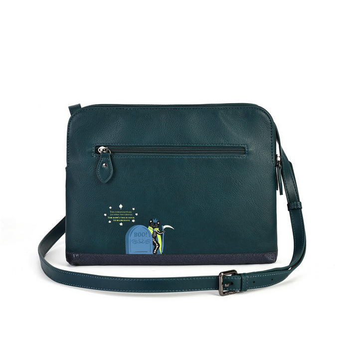 A dark teal leather crossbody bag with a front zippered pocket, a matching shoulder strap, and a small graphic print on the lower left front pocket featuring a tombstone and the text 'GOOD LUCK'.