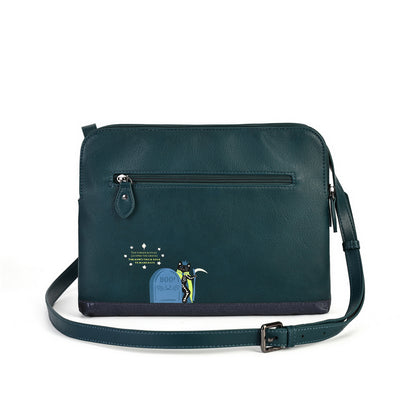 A dark teal leather crossbody bag with a front zippered pocket, a matching shoulder strap, and a small graphic print on the lower left front pocket featuring a tombstone and the text 'GOOD LUCK'.