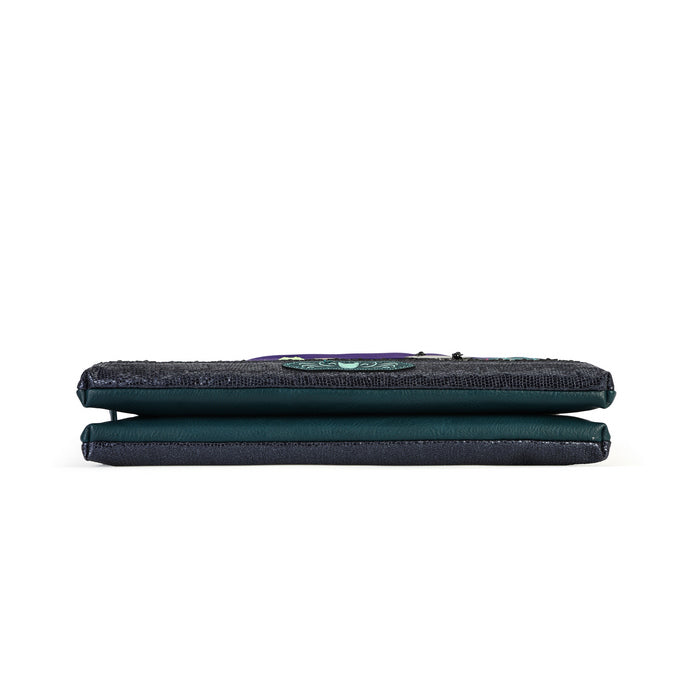 A dark teal-green fabric pouch or wallet with a textured top flap and a small colorful embroidered patch, shown from the side on a plain white background.