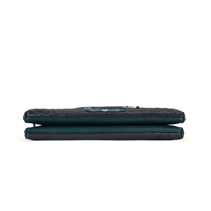A dark teal-green fabric pouch or wallet with a textured top flap and a small colorful embroidered patch, shown from the side on a plain white background.