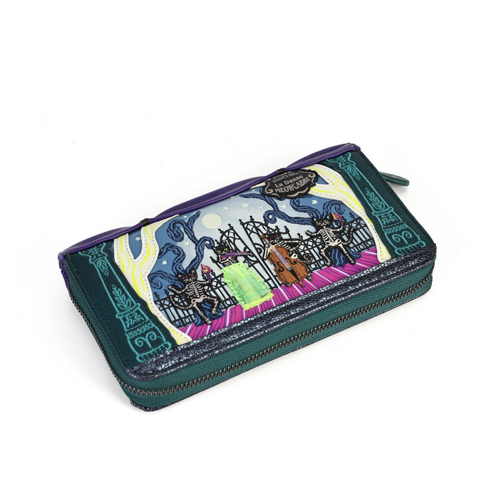 A zip-around wallet featuring a colorful illustration of a witch riding a broomstick under a starry night sky, with purple trim and a dark green base.