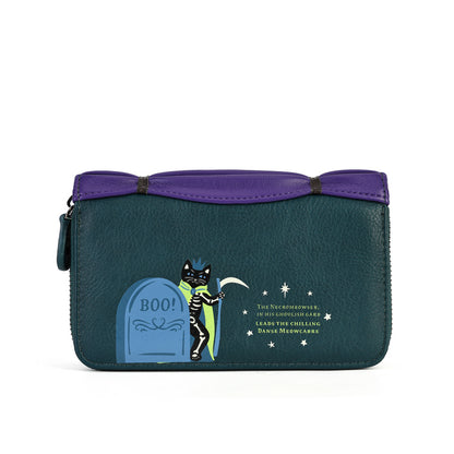 A rectangular zip-around clutch bag with a dark teal body and a purple top handle, featuring a Halloween-themed graphic of a skeleton cat standing next to a blue tombstone with the word 'BOO!' and small white stars and text on the front.
