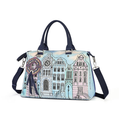 A structured handbag with a light blue and pink watercolor-style illustration of classic European canal houses. The bag features dark navy blue handles, a matching navy blue shoulder strap, silver-tone hardware, and a decorative circular charm hanging from the side.
