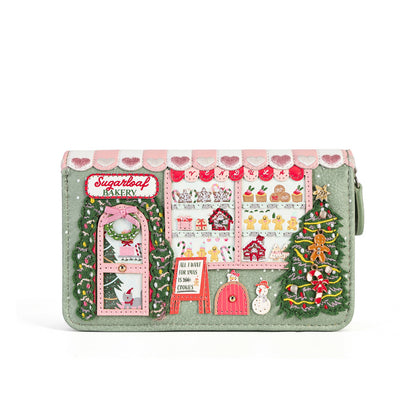 A mint green zip-around wallet featuring a detailed Christmas market scene design on the front, complete with a bakery storefront, decorated Christmas trees, a pink awning with hearts, and small embroidered details.