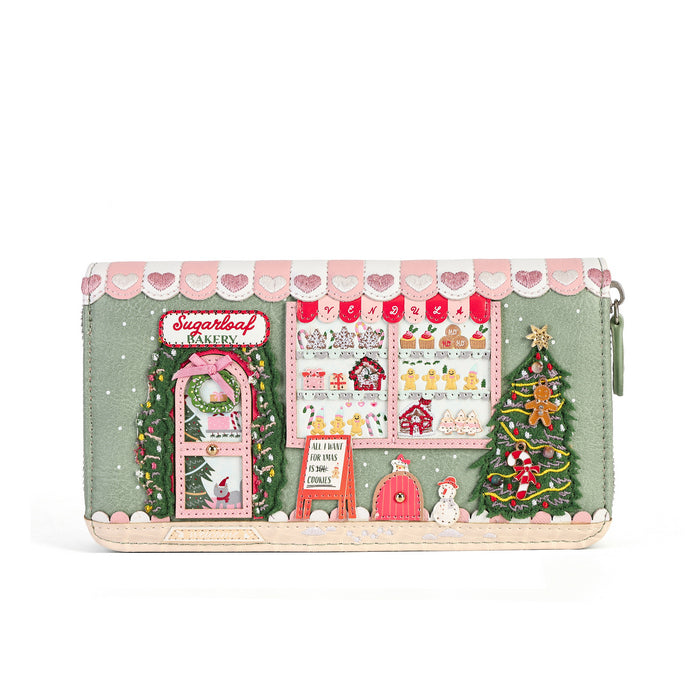 A long wallet with a whimsical Christmas bakery design, featuring embroidered details of a decorated tree, a pink gift box, a snowman, and a bakery window display on a sage green background.