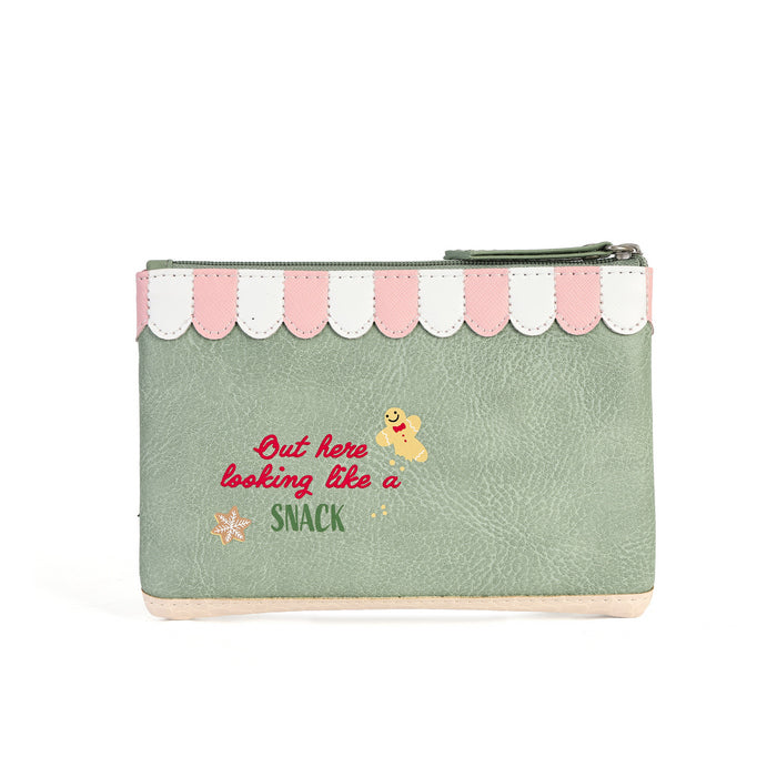 A mint green faux-leather zippered pouch with a pink and white scalloped top border. The front features a red embroidered quote reading 'But here looking like a SNACK' alongside a small yellow cartoon character and a tiny orange flower.