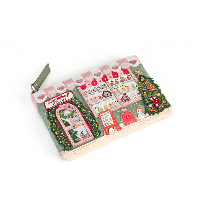 A rectangular fabric pouch with a green zipper, featuring a detailed Christmas storefront design in pink, red, green, and white, photographed on a white background.