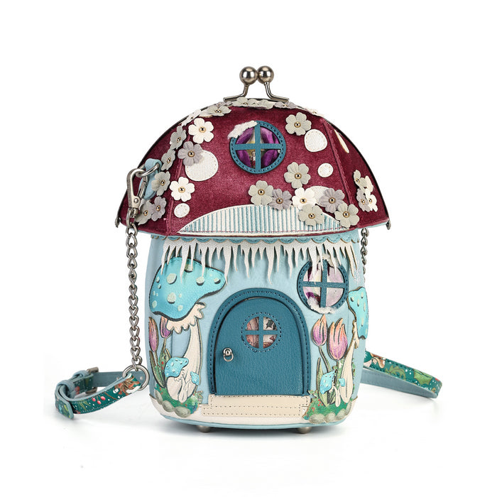 A whimsical, fairy-tale-inspired house-shaped handbag with a mushroom cap roof, blue door, and floral details, shown on a plain white background.