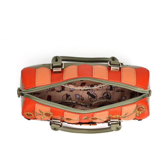 An open handbag with a patchwork exterior in orange, peach, and olive green, featuring floral embroidery on the front, a patterned interior lining, and top handles on a white background.