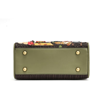 An olive green clutch handbag with a dark brown textured base, decorated with colorful embroidered figures along the top edge and four gold-tone metal studs on the front.