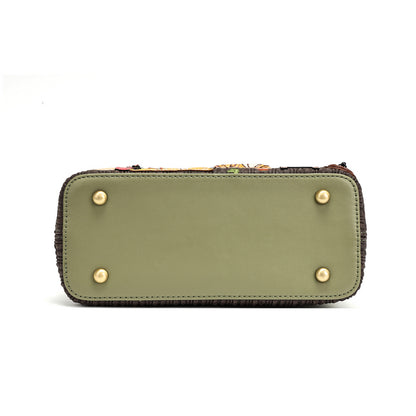 The bottom view of a rectangular handbag or clutch in olive green leather with four gold-tone metal studs on the base and a dark fringed edge, shown on a white background.