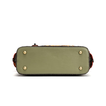 The bottom view of a structured handbag in olive green leather, featuring four gold-tone metal studs on the front and sides, a dark textured trim, and a hint of a patterned strap at the top, set against a plain white background.
