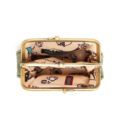 Top-down view of an open kiss-lock handbag showing a beige printed fabric lining with black illustrations and a small red phone motif, framed in gold-tone metal.