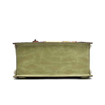 A sage green leather clutch purse shown from the back, featuring a textured leather back panel, stitched edges, and a small decorative clasp on top, set against a plain white background.