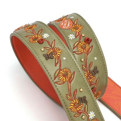 An olive green leather strap featuring detailed floral embroidery in orange, yellow, and brown, with small white daisy accents and brass studs. The inner lining is a vibrant orange-red.