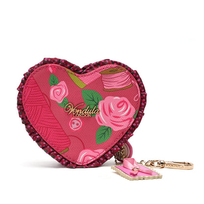 A heart-shaped pink fabric pouch with embroidered roses, green leaves, and a pink spool motif, featuring a dark pink beaded border and a gold-tone keychain with a pink bow charm.
