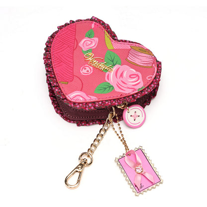 A heart-shaped pink sewing-themed keychain pouch with rose and floral patterns, a gold-tone chain clasp, a pink button charm, and a decorative tag, shown on a white background.