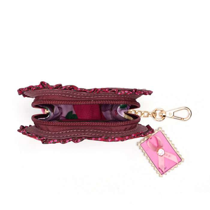 A burgundy fabric zippered pouch with a ruffled edge, shown open to reveal a floral-patterned interior. It has a gold-tone chain and clasp, with a pink decorative tag attached.