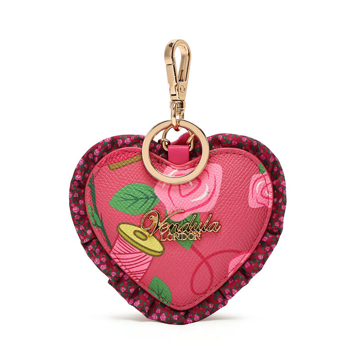 A heart-shaped keychain pouch by Vendula London, featuring a pink floral pattern, a gold-tone clasp, and a ruffled magenta border with small pink flowers.