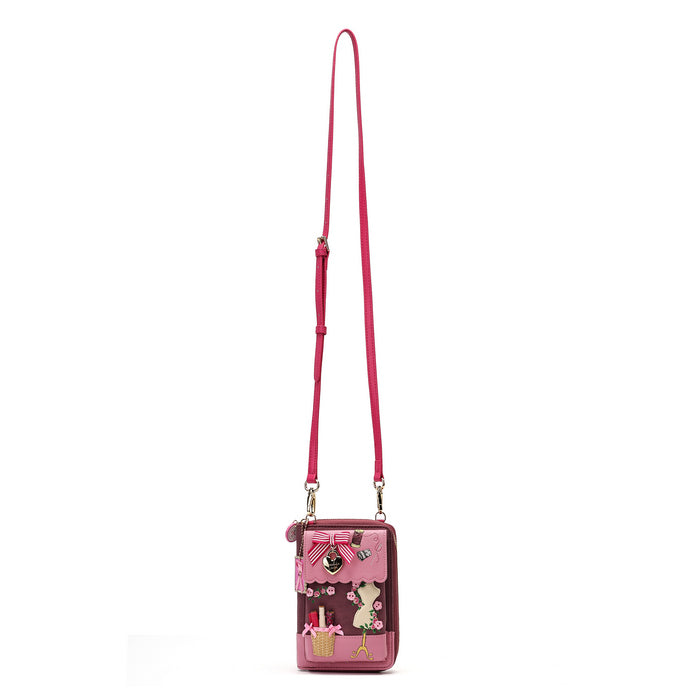 A pink crossbody phone bag with a long strap, featuring a cartoon bunny design and small decorative charms on a plain white background.