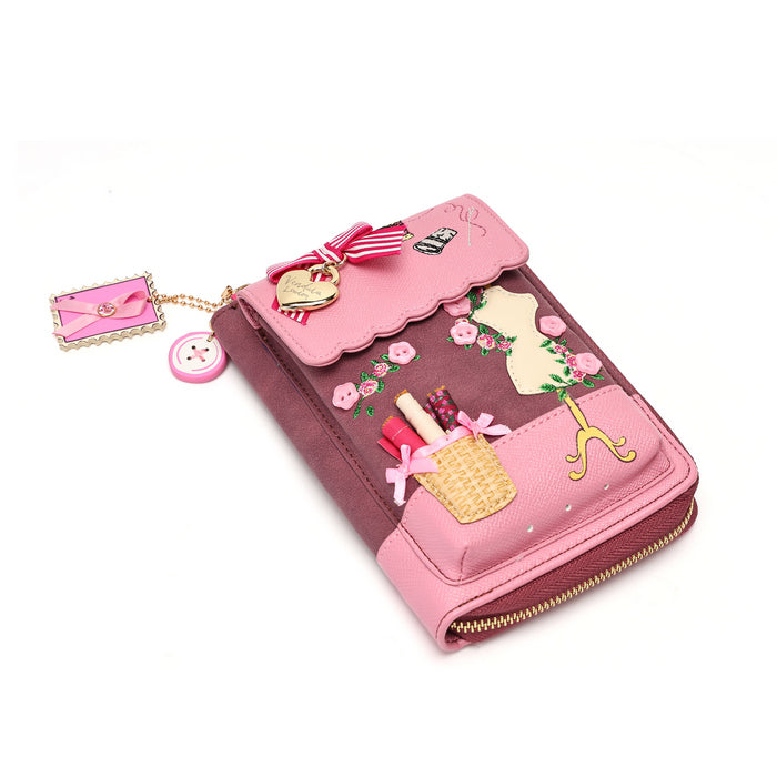A pink and burgundy zip-around wallet decorated with 3D floral and fashion-themed embellishments, including a miniature handbag, lipstick, hat, and ribbon, shown on a white background.