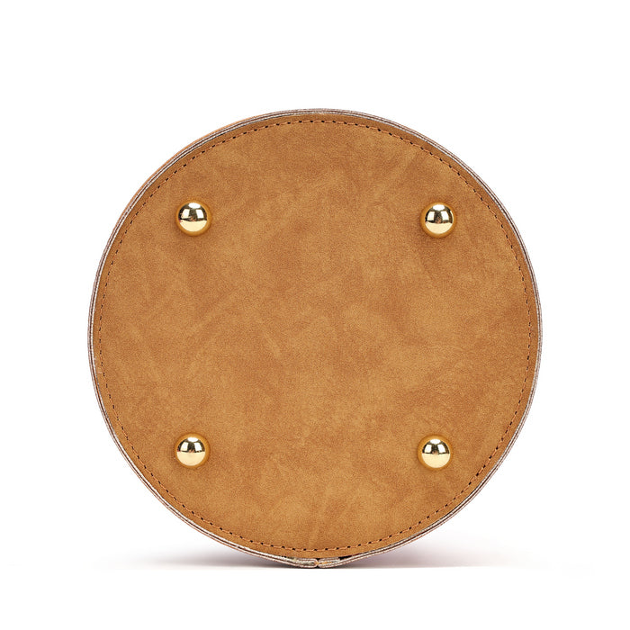 A circular tan faux-leather clutch or bag base with four gold-tone metal studs, shown from a top-down view on a white background.