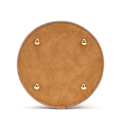 A circular tan faux-leather clutch or bag base with four gold-tone metal studs, shown from a top-down view on a white background.