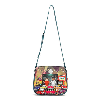 A teal shoulder bag with a colorful, detailed graphic print on the front pocket depicting a street scene with a man in a white suit, red cars, and a neon sign. The bag has a long teal strap and is shown against a plain white background.