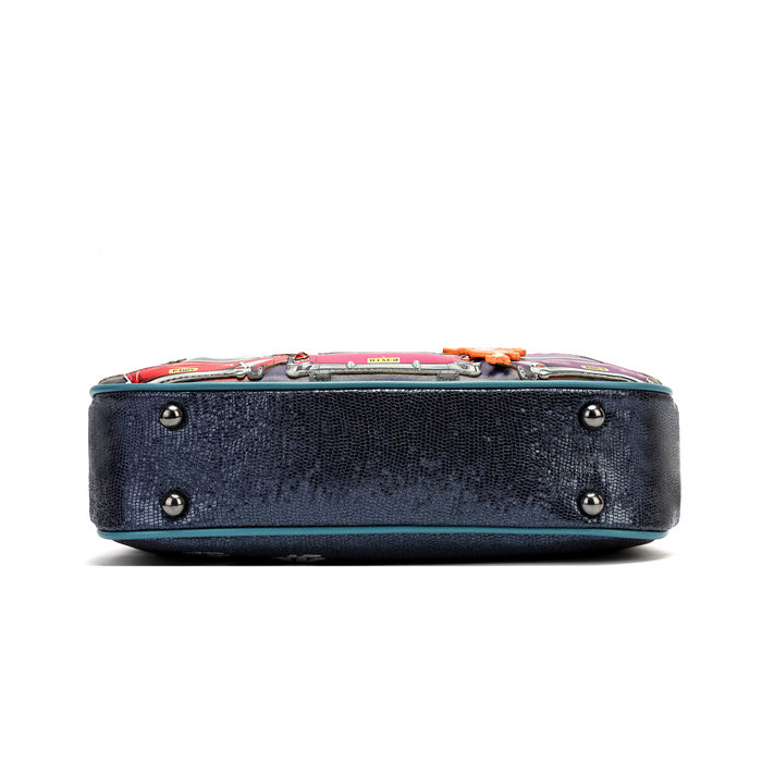 The bottom view of a Gucci handbag showing a dark navy blue textured leather base with silver studs, a turquoise piping edge, and a colorful patterned leather top panel with horsebit hardware.
