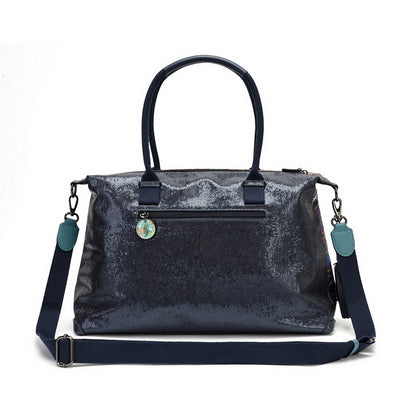 A navy blue sequined handbag with dark navy handles and a matching adjustable shoulder strap, featuring a small round decorative charm on the front pocket, set against a plain white background.