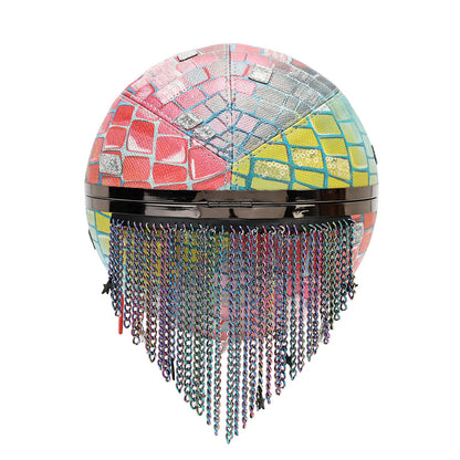 A spherical decorative object with a mosaic tile pattern in pink, blue, yellow, and silver, featuring a glossy black horizontal band and hanging iridescent chains below, shown on a plain white background.