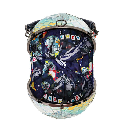 A spherical clutch handbag with a mosaic tile pattern on the top and bottom, and a dark space-themed print featuring astronauts, a disco ball, and the word 'INNOVATION' on the front, framed by a silver-tone metal clasp.