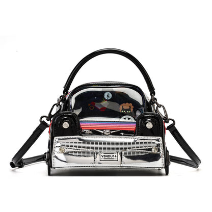 A novelty handbag designed to look like a classic car grill, featuring a shiny silver front grille, black sides, a black top handle, and a clear plastic top window showing cartoon stickers inside. A small label on the front reads 'VANDU14'.