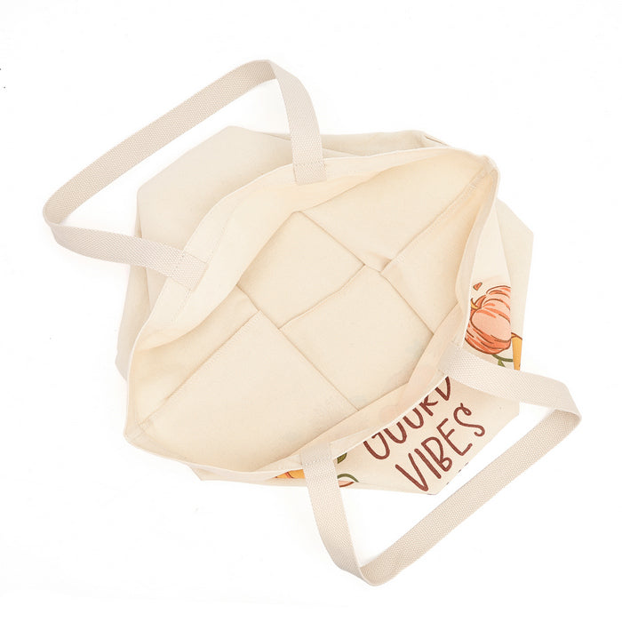 An off-white canvas tote bag with dual shoulder straps, featuring a printed graphic of a pumpkin and the text 'DUTY VIBES' on a clean white background.