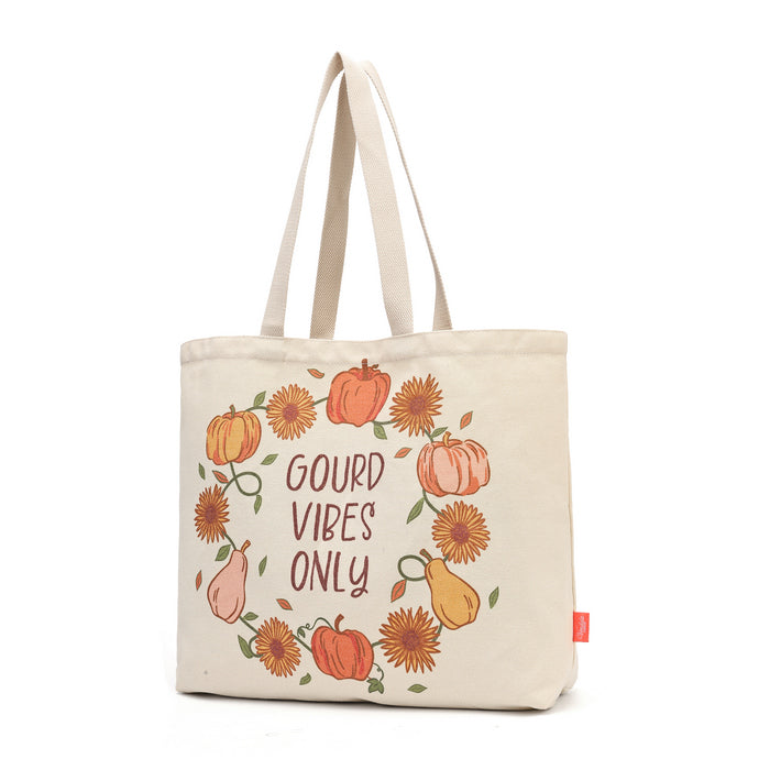 A cream-colored canvas tote bag featuring a circular autumn-themed illustration with pumpkins, sunflowers, pears, and the text 'GOUD VIBE'S ONLY' in brown lettering, shown against a plain white background.