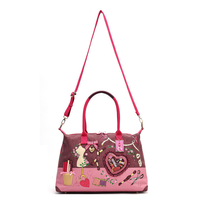 A roomy holdall for travel, busy days or carrying extra essentials, with twin handles and an adjustable detachable strap. The sewing-themed artwork combines cotton reels, ribbons, scissors and rose motifs with Pink Ribbon details, finished with hand-stitched accents.
