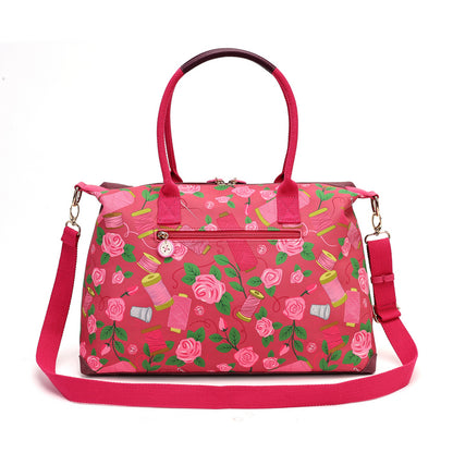 A roomy holdall for travel, busy days or carrying extra essentials, with twin handles and an adjustable detachable strap. The sewing-themed artwork combines cotton reels, ribbons, scissors and rose motifs with Pink Ribbon details, finished with hand-stitched accents.
